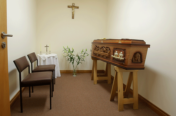 Engraved wooden coffin in a private room with white lilies
