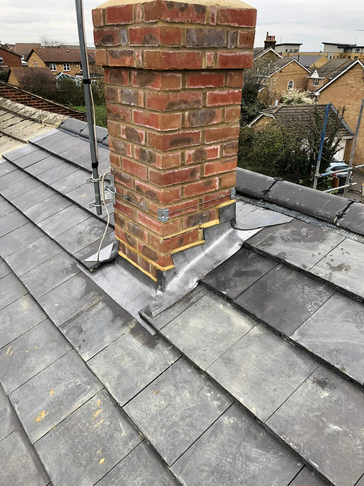 Lead flashing around brick chimney on slate roof.