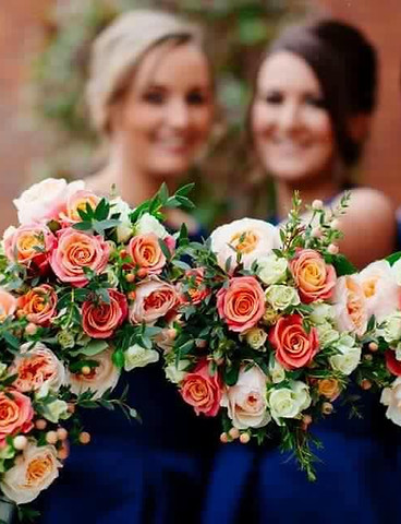 Bridesmaids in navy dresses, holding beautiful cream and pink flower bouquets