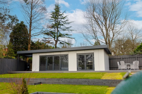 Grey and cream newly built garden room in a back garden with green grass