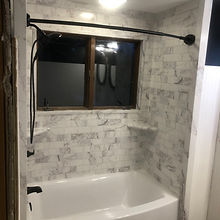Bath tub with tile surround. Tiles is a 3 inch by 6 inch multi colored tile.