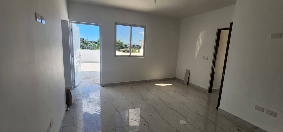 Bright bedroom with tiled floor, window, and direct access to an outdoor terrace area.