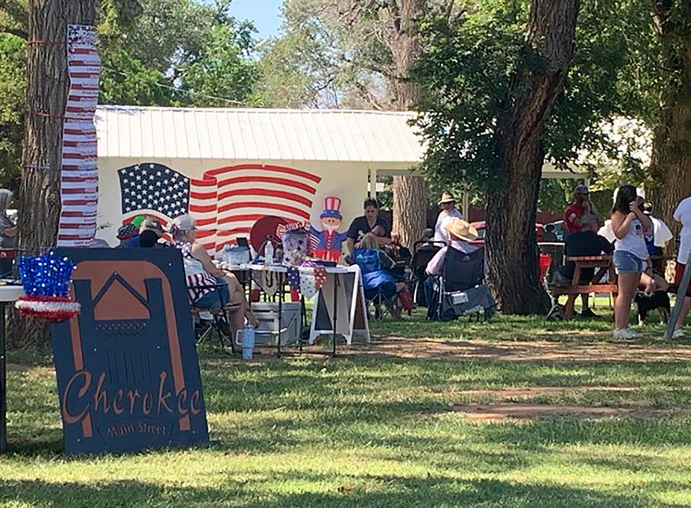 The pavilion at Cherokee City Park features an American Flag mural. People are gathered for the anual Fourth of July event.