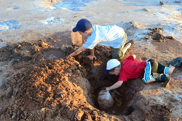 Two young boys mine for hourglass selenite crystals from holes dug in the digging area at Great Salt Plains.
