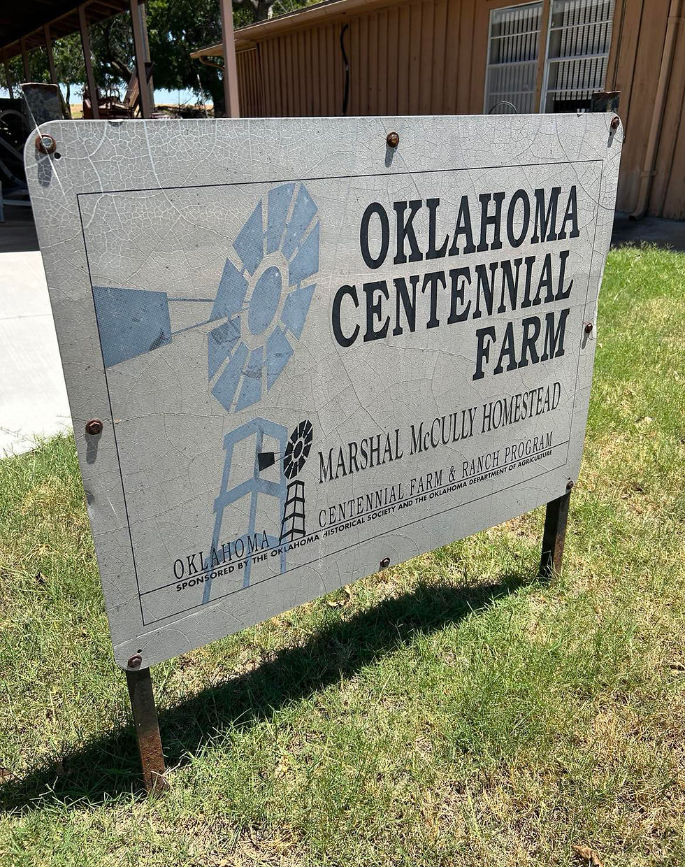 A sign in front of Sod House Museum in Aline, Oklahoma, reads "Oklahoma Centennial Farm - Marshal McCully Homestead - Centennial Farm & Ranch Program - Sponsored by the Oklahoma Historical Society and the Oklahoam Department of Agriculture." The sign features drawings of small windmills.