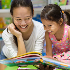 Parent and child reading books together in the library.