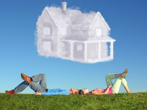 Cloud shaped like a home with young couple laying in the grass below it