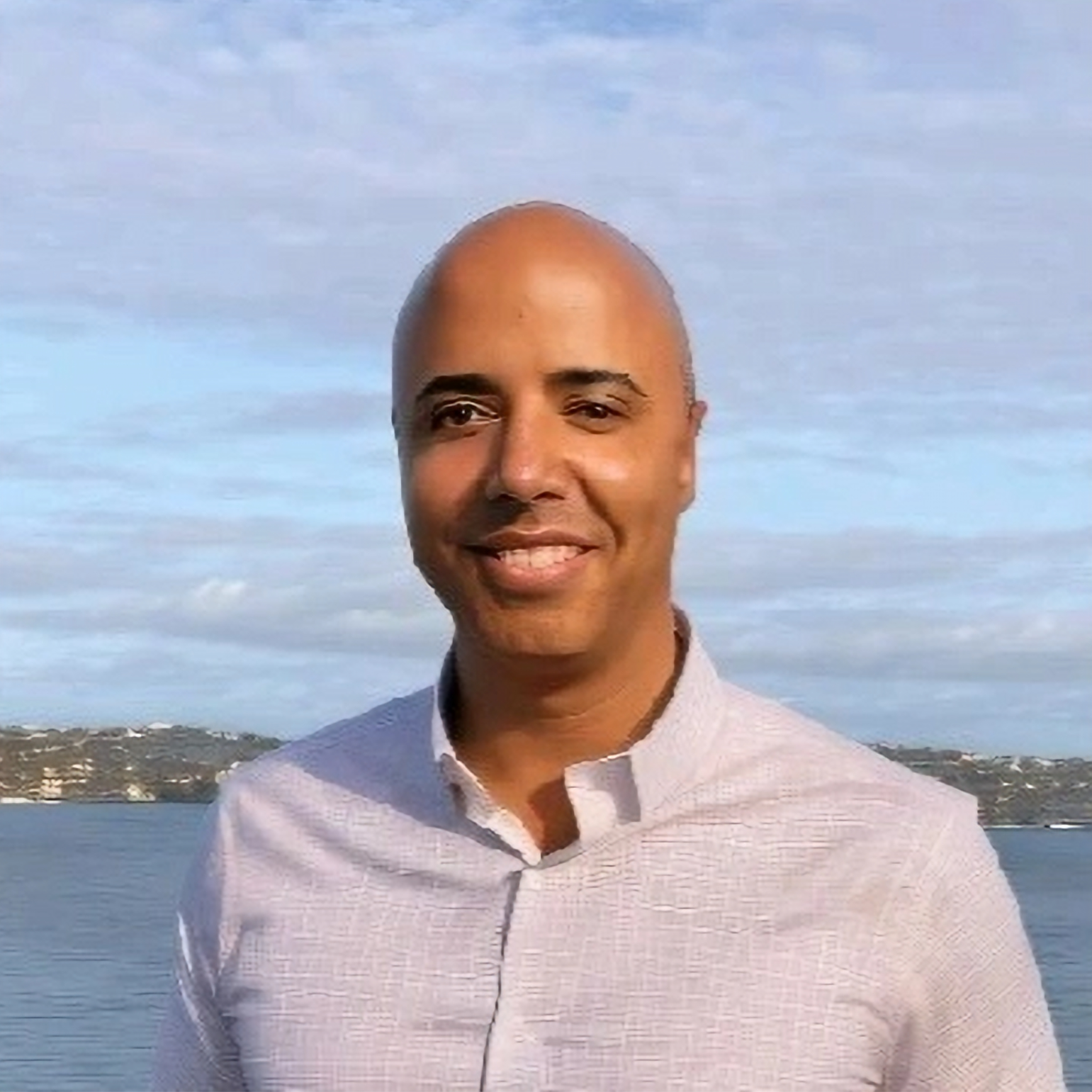 Colby Verett, professional headshot outdoors with water and blue sky background
