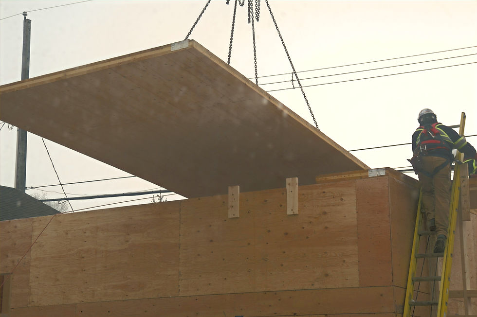 Cross laminated timber panels being installed with a crane. Worker on a ladder.
