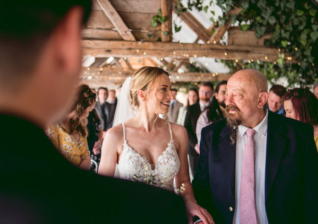 bride laughing with dad walking down the aisle