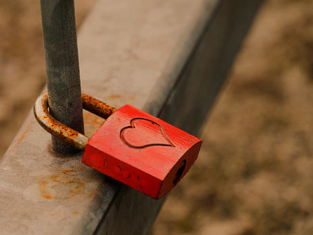 un cadenas rouillé avec un coeur gravé est fixé à une barrière