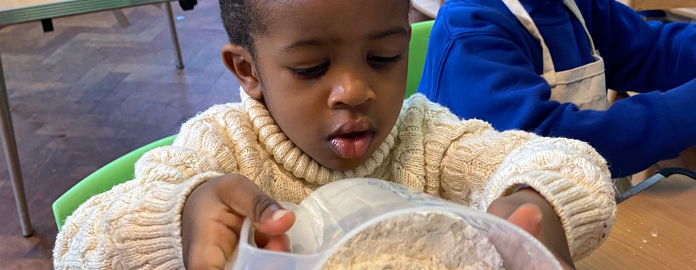 Young boy pouring flour into bowl as part of cooking projects with toddlers at Shining Stars Nursery in Cardiff