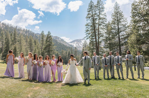 Bride and groom walking with wedding party across mountain meadow during Lake Tahoe wedding portraits.