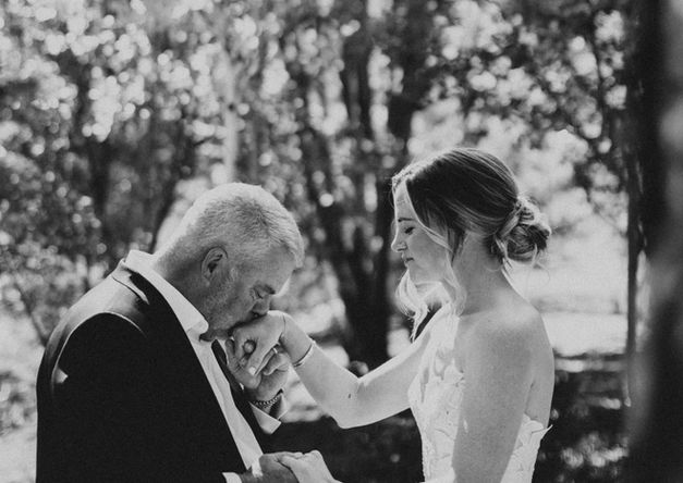 Bride and groom holding hands and laughing during ceremony vows in mountain setting.