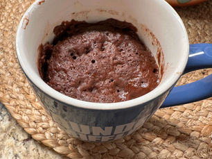 Chocolate mug cake freshly cooked in a microwave-safe mug, showing a soft, fudgy texture.