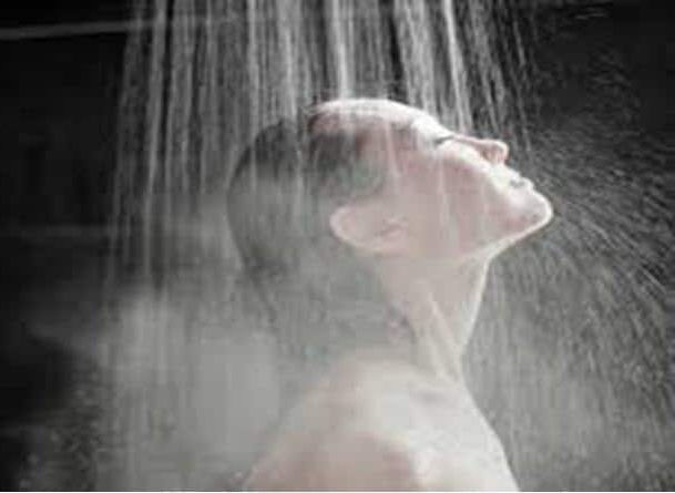 A lady standing under a shower surrounded by steam