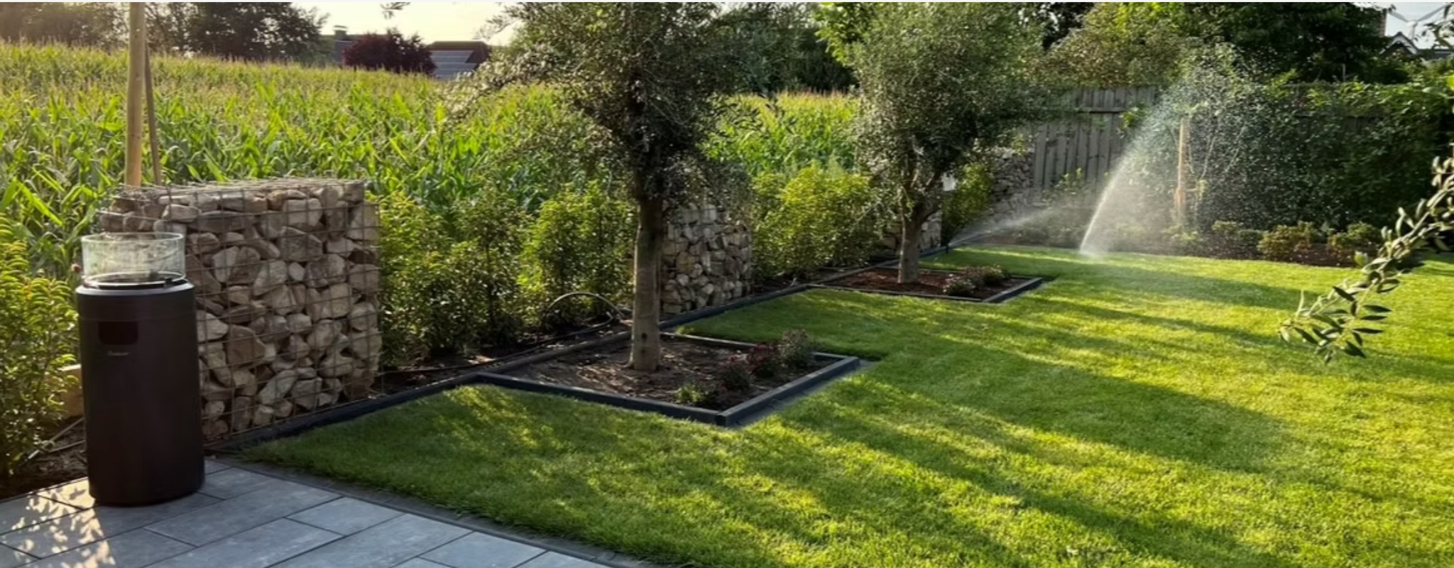 Gepflegter Garten mit laufender Rasenberegnung und mehreren Wasserstrahlen