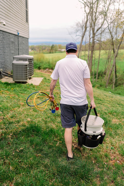 HVAC technician carrying HVAC gauges and bucket