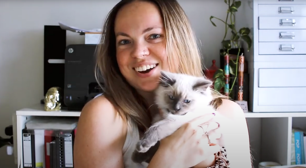 Carley holds a ragdoll kitten and smiles from her studio.