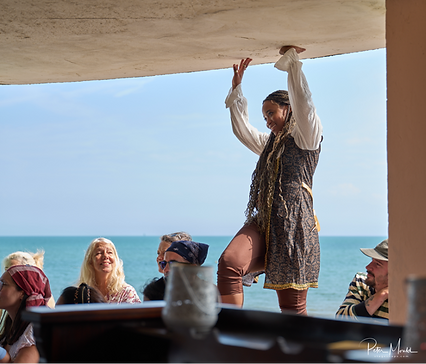 A photo of a woman in a pirate outfit, with the sea behind her