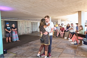 A photograph of man and a woman dancing, with audience members behind them