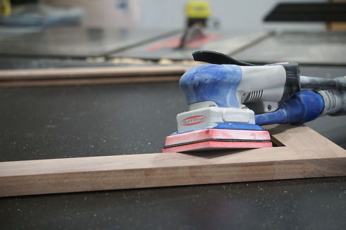 A sander leaning against a wood cabinet frame.