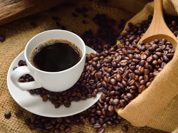Eine Tasse schwarzen Kaffee und Kaffeebohnen