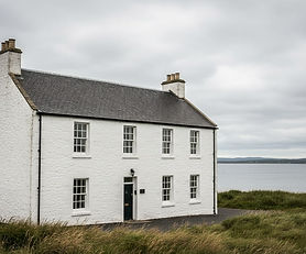 Traditional Scottish Highland hotel building in Ardersier with white stone facade, slate roof, and coastal Moray Firth backdrop, commercial hospitality property exterior view