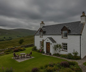 Traditional Scottish Highland self-catering cottage in Ardclach with whitewashed stone walls, slate roof, and garden area surrounded by rolling countryside with dark atmospheric overlay