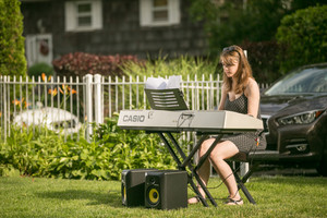 young female student sitting next to teacher on the bench while learning how to play piano