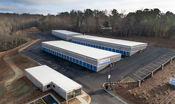 An aerial view of a storage facility in Oakwood, GA that has blue doors, drive up self storage, climate control storage, and a security fence surrounding the property.