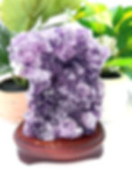 White and purple amethyst cluster on a reddish-brown wood base