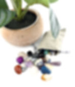 Many small multi-colored stones spilling out of a gray crushed velvet pouch.