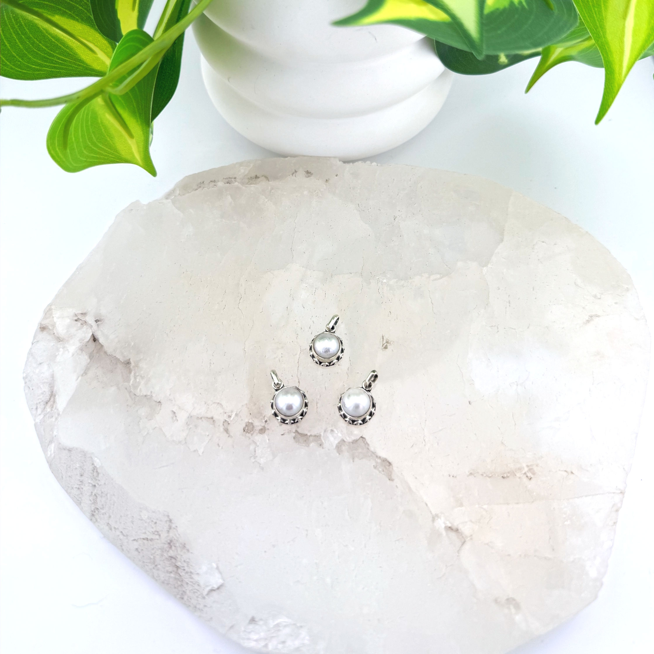 Small round silver pendant. Some filigree around edges. White pearl in center.