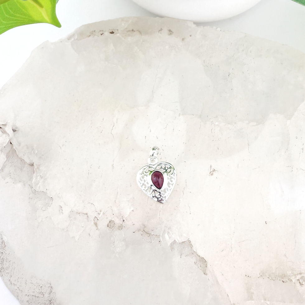 Filigree filled, heart shaped silver pendant with dark red stone. 