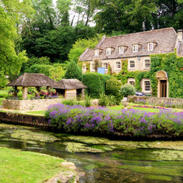 A beautiful old mansion covered with ivy, surrounded by a meticulously landscaped garden, reflecting historical landscape restoration prowess