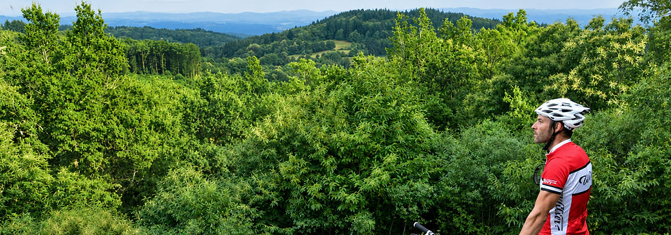 a mountain biker MTB on top of a mountain overlooking the tree filled view in La Creuse