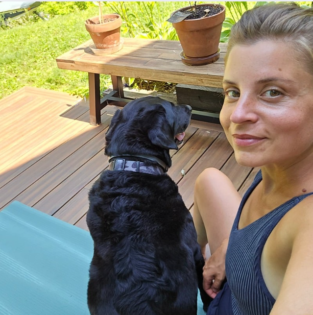 Paige Jordan of Natural Nest Interiors sitting on her deck with her dog — connecting with nature and the slow, intentional rhythm that inspires her approach to home design.