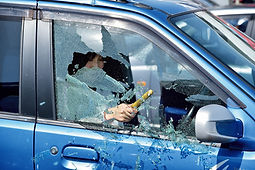 ハンマーで車の内側からガラスを割る女性