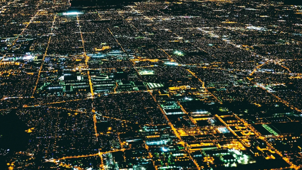 An aerial night view of a densely populated metropolitan grid 