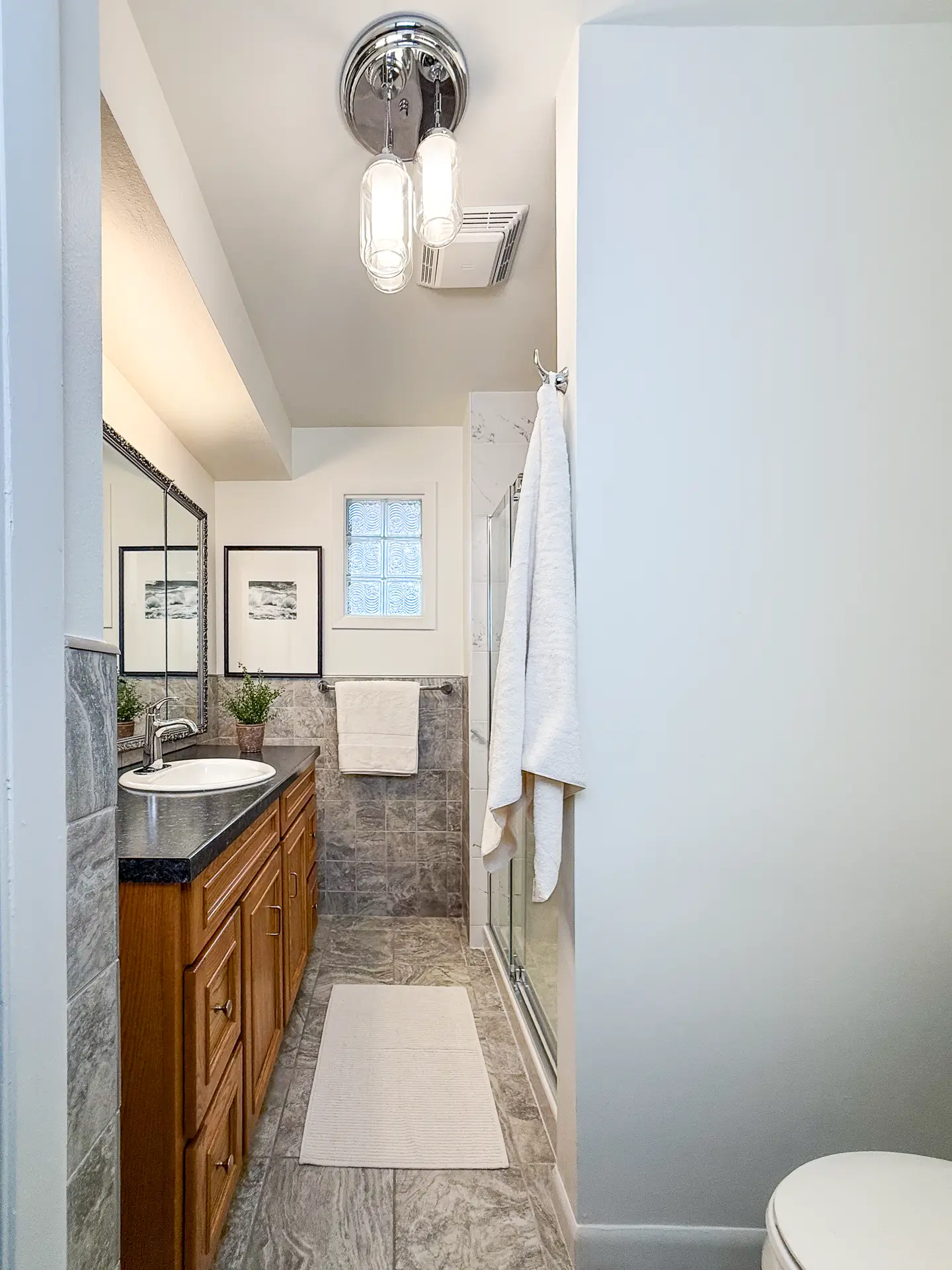 Bathroom renovation before and after – natural wood vanity with black countertop and soft lighting