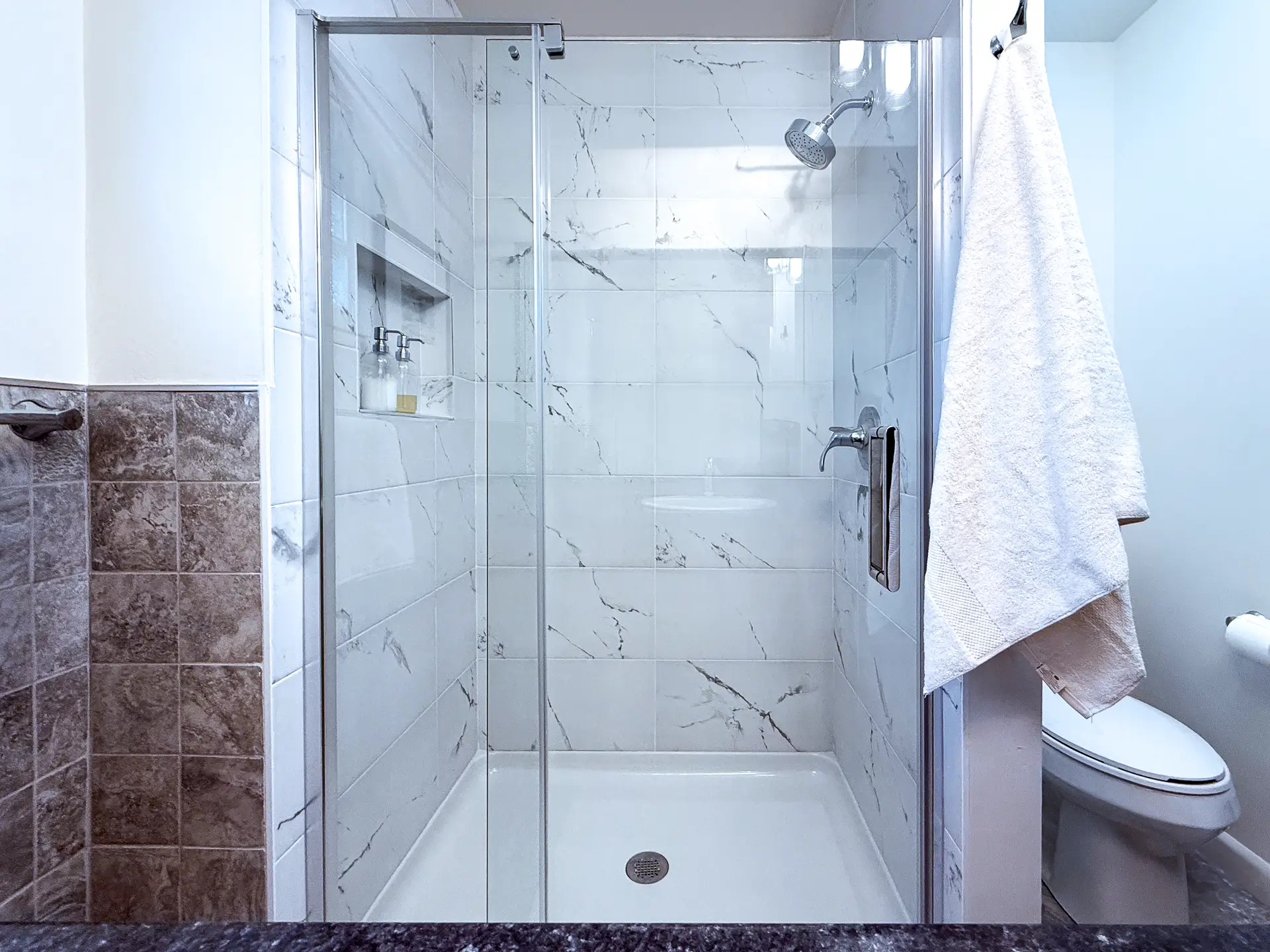 Bathroom renovation before and after – walk-in shower with earthy tile and rainfall fixture