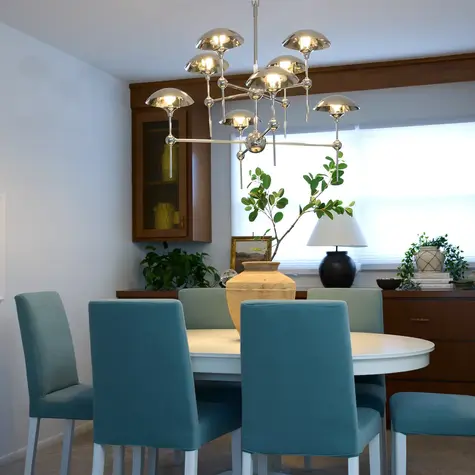 Cozy dining setup featuring teal velvet chairs, a round white table, and organic curves.