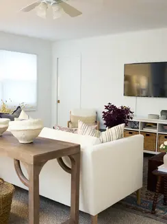 Cozy media lounge with tailored linen sofa, deep blue ottoman, layered pillows, and natural wood accents