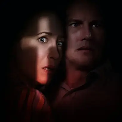 Ed and Lorraine Warren are shown in front of a dark background. It's a zoom-in on their faces to show the horror on them. On Lorraine's face we can see light in the shape of a cross.