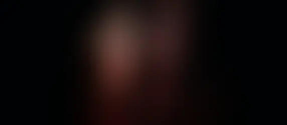 Ed and Lorraine Warren are shown in front of a dark background. It's a zoom-in on their faces to show the horror on them. On Lorraine's face we can see light in the shape of a cross. 