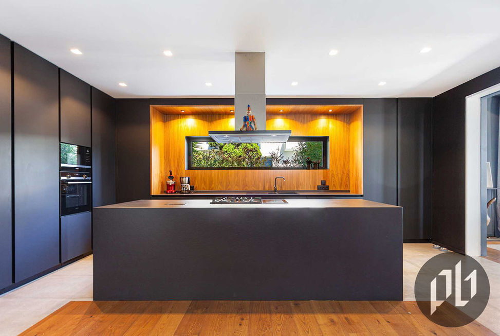 Cozinha de luxo em tons de preto fosco com nicho em carvalho e janela para jardim.