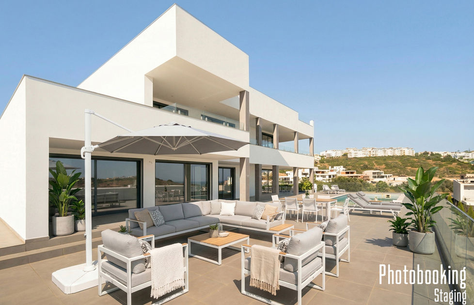 Zona lounge exterior com sofás premium, guarda-sol cinza e plantas decorativas.