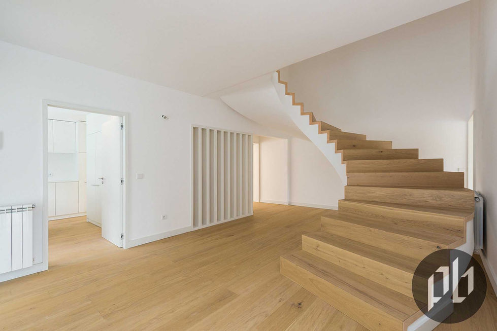 Escada escultural em carvalho com curvas orgânicas em interior minimalista branco.