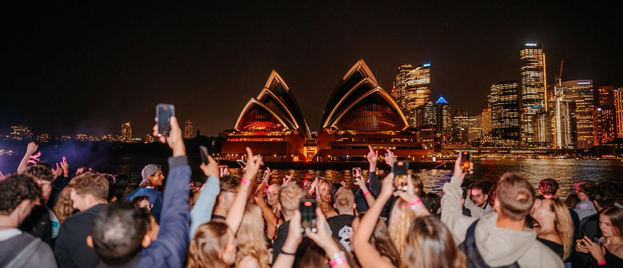 Crowd enjoying Aloha Sydney night event with Sydney Opera House in the background